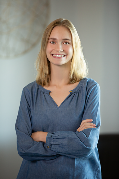 Smiling woman in a long sleeve top with hands crossed at her chest