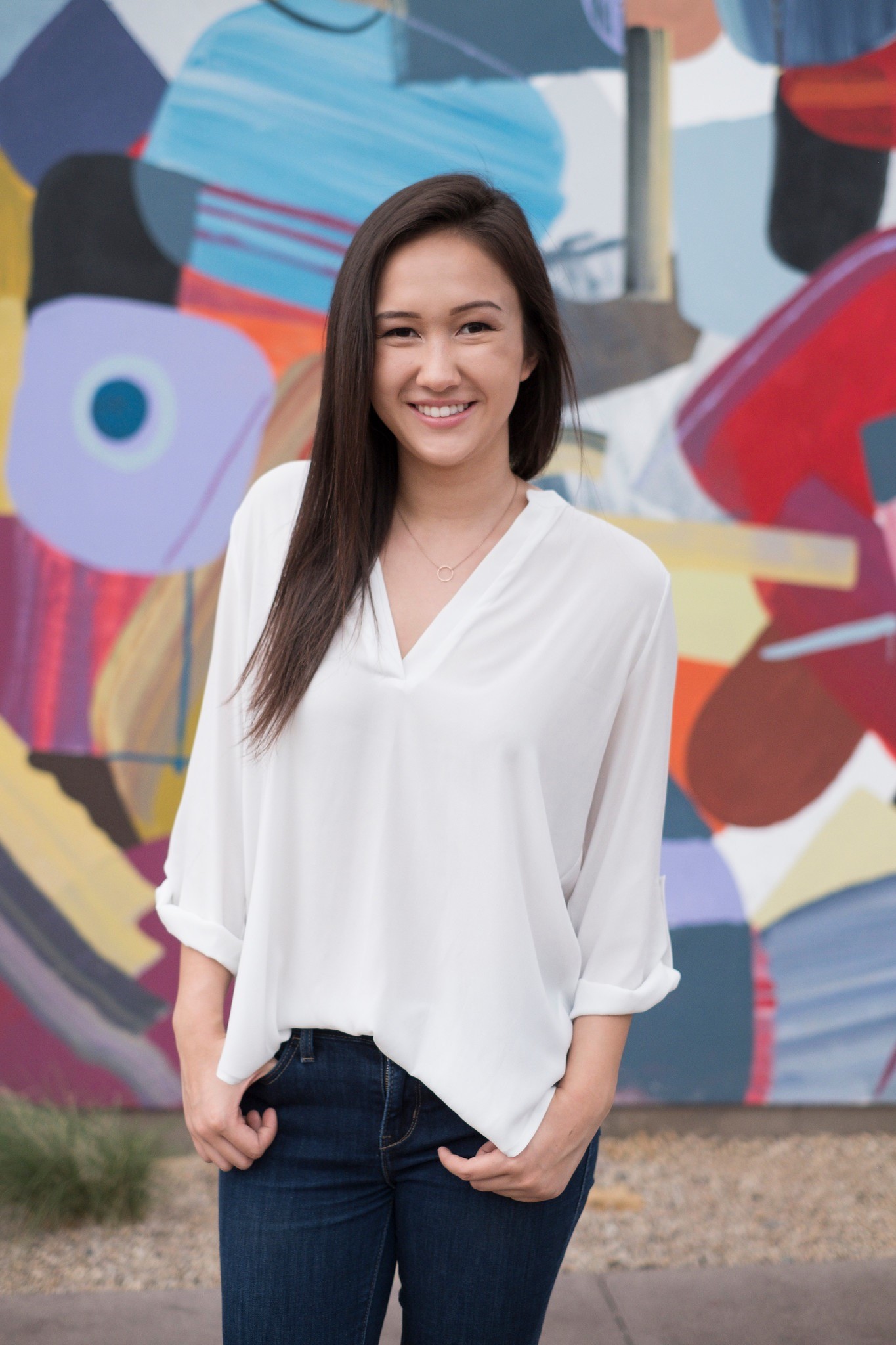Photo of woman in white shirt in front of a colorful mural 